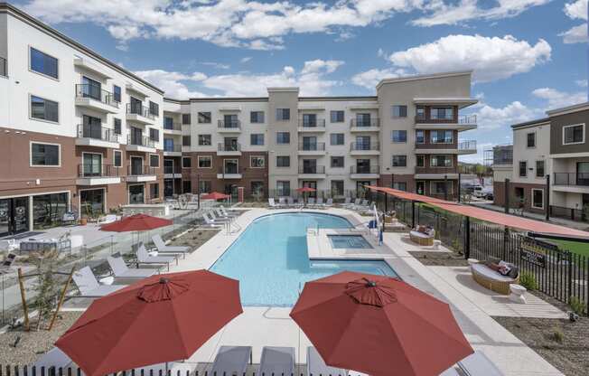 Icon at Cooley Station-Swimming pool with red umbrellas in front of 4 story apartment building