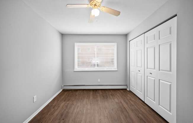 an empty bedroom with a ceiling fan and a window