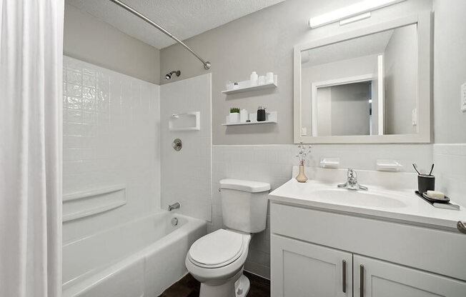 Model Bathroom with White Cabinets, Wood-Style Flooring and Shower/Tub at Middlesex Crossing Apartments in Billerica, MA.