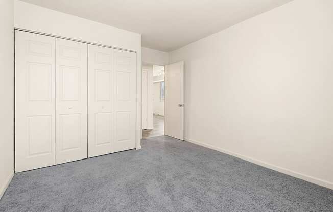 A room with white walls and a grey carpet.