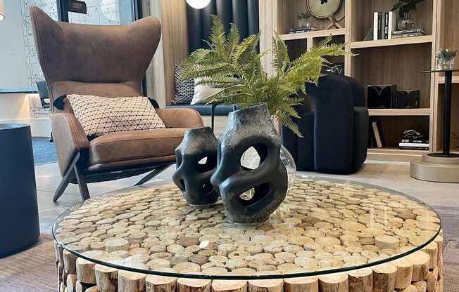 a coffee table made out of logs with two black vases on it