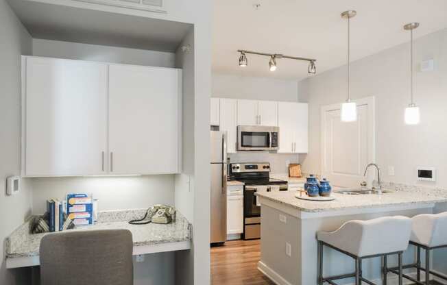A kitchen with white cabinets and a grey counter.