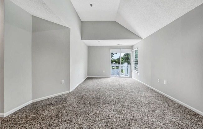 an empty living room with a door to a balcony