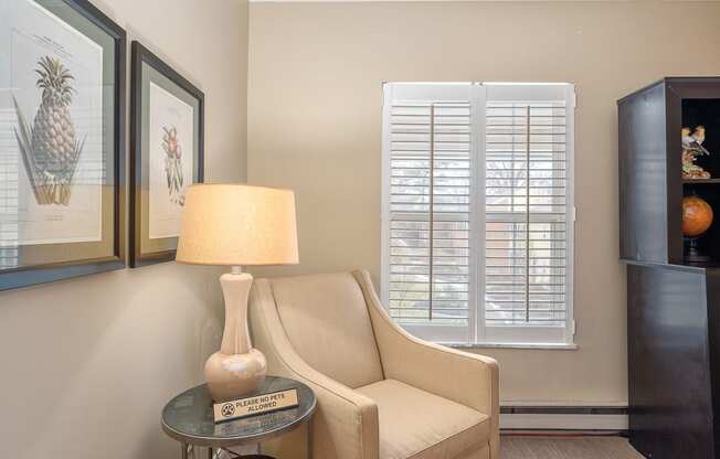 a living room with a chair and a lamp and a window