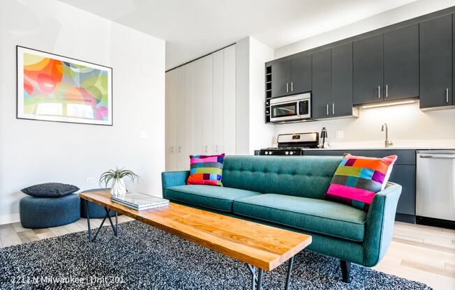 Vibrant green sofa in L Logan Square Apartments, complemented by a stylish kitchen in the background, creating a contemporary and inviting living space