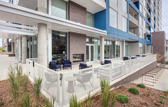 an outdoor patio with chairs and a fireplace at an apartment building