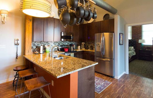 Lofts at Lafayette Square kitchen with dark cabinets, granite countertoips, stainless steel appliances, plank flooring and tile backsplash