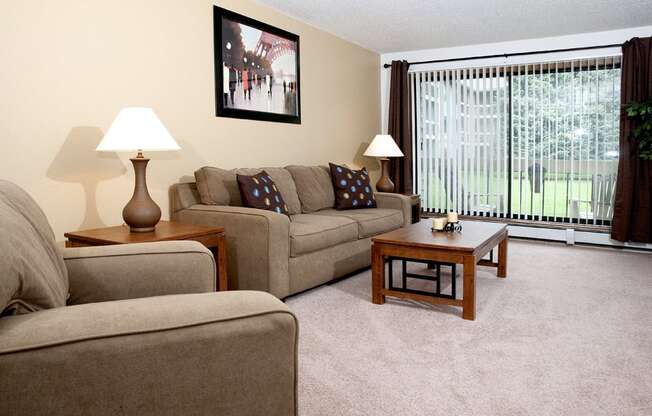 Living room with couch, chair, coffee table, and a view of a patio