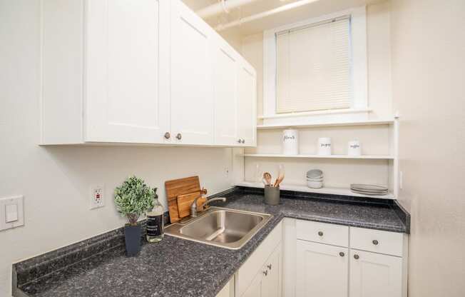 a kitchen with white cabinets and granite counter tops and a sink