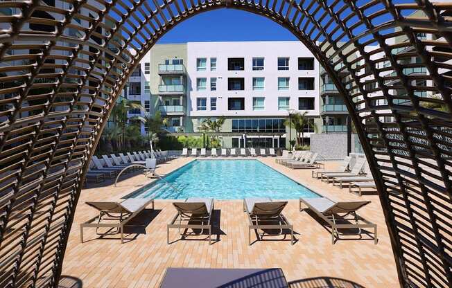 a swimming pool with chairs and a building in the background