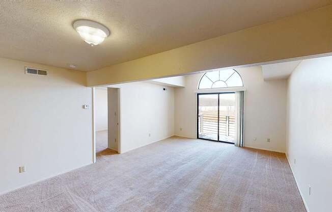 spacious living room with a cathedral ceiling and a door to a balcony at South Bridge Apartments in Fort Wayne, Indiana