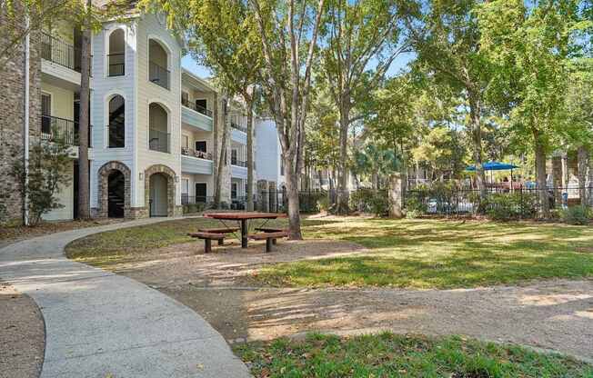 A park with a picnic table and apartment buildings in the background.