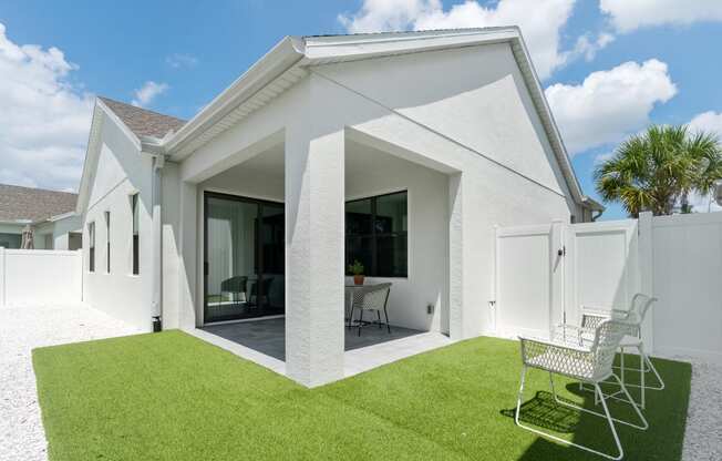 the exterior of a white house with a lawn and two chairs at Odyssey, Florida