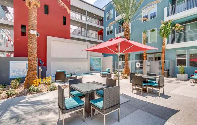 A patio with a table and chairs under a red umbrella.