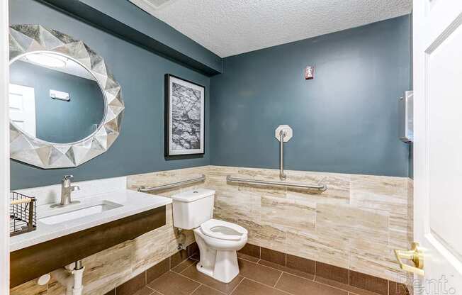 A bathroom with a toilet, sink, and mirror.