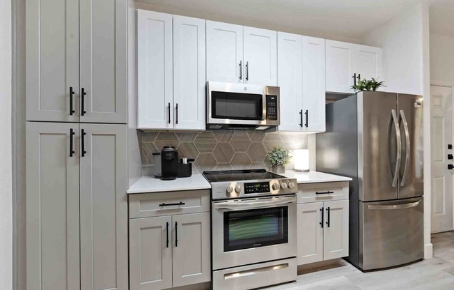 A modern kitchen with stainless steel appliances and white cabinets.