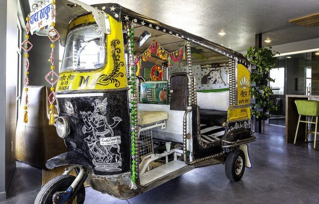 A decorated auto rickshaw is parked inside a building.