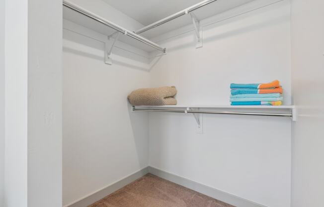 a white closet with shelves and towels on a shelf