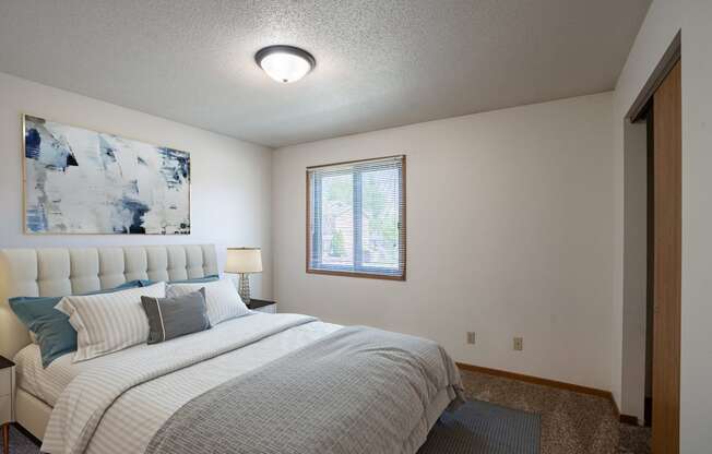 a bedroom with a bed and a window.Fargo, ND Southview Village Apartments