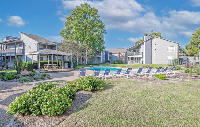 A sunny day at a Laurel Parc apartment complex with a pool and lounge chairs at Laurel Parc apartments in Shreveport, LA.