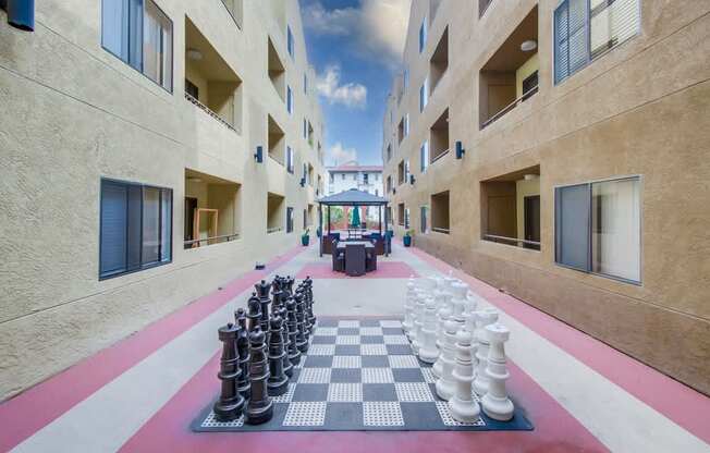 A giant chess board is set up in the courtyard of a building.