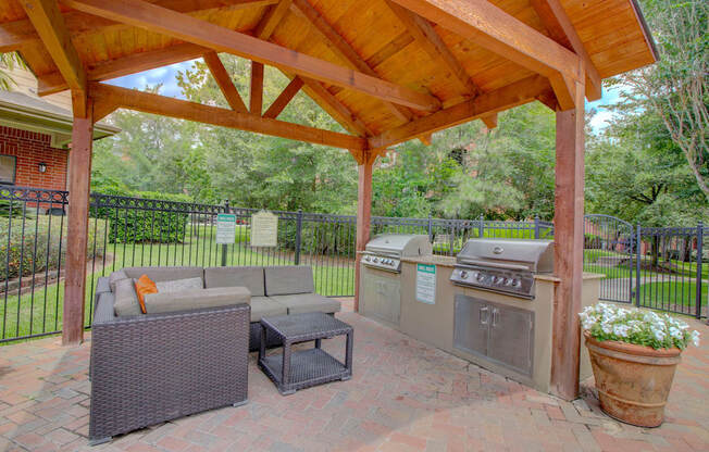 an outdoor kitchen with a grill and a seating area under a wooden awning