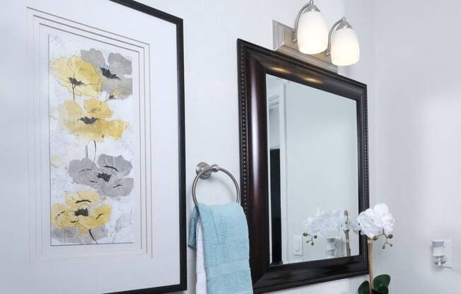 Bathroom in Fifteen 50 Apartments Las Vegas with floral art, vanity mirror, and sink with storage.