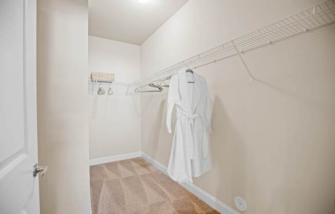 A white robe is hanging on a rack in a small, empty room.