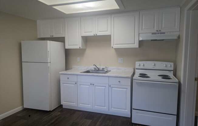 a kitchen with white cabinets and appliances and a white refrigerator