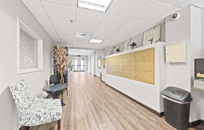 a long hallway with a chair and a table and a wall with a bulletin board