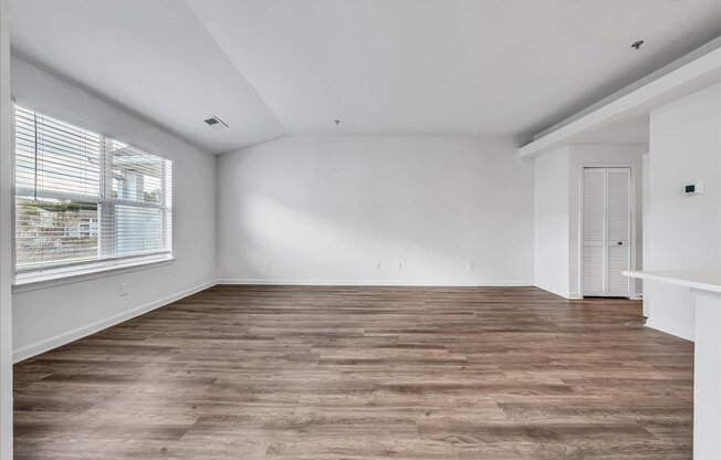 the living room of a home with a large window and wooden floors