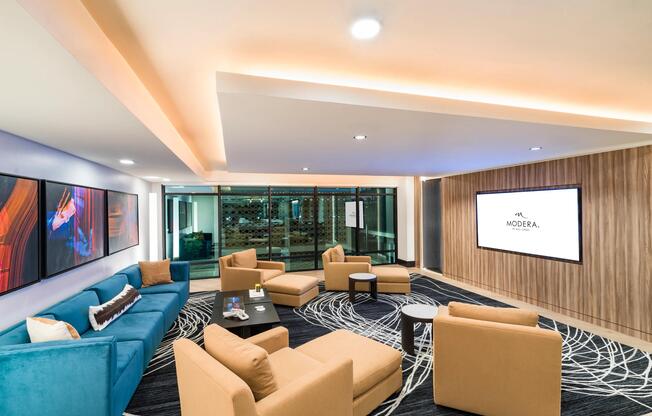 Bold colors and modern textures bring a vibrant energy to this clubroom featuring a media screen, perfect for casual hangouts or low-key movie nights.