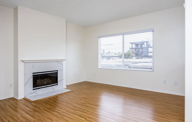 an empty living room with a fireplace and a window