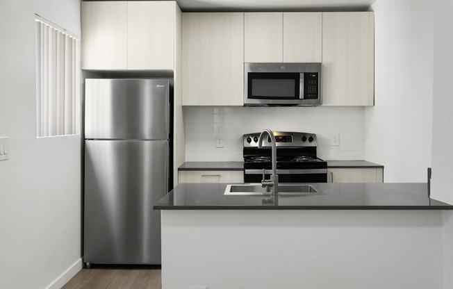 A kitchen with a stainless steel refrigerator and microwave above a counter.