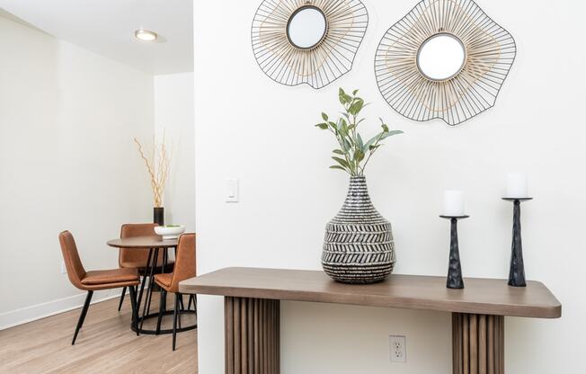 a dining area with a table and chairs and a large mirror on the wall