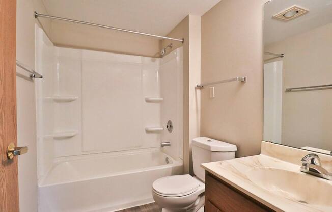 A white toilet sits next to a white bathtub in a bathroom.