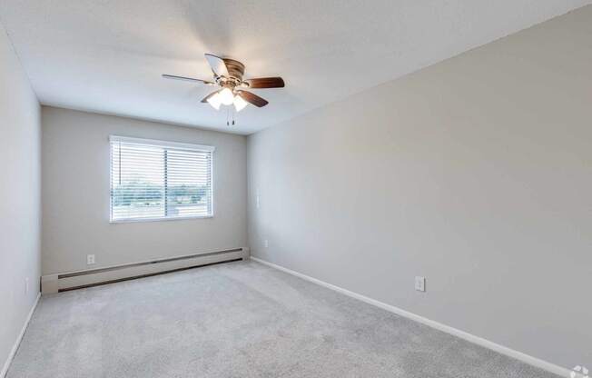 an empty living room with a ceiling fan and a window