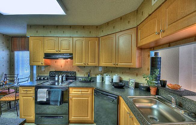 Kitchen with cabinets, sink, black oven and dishwasher