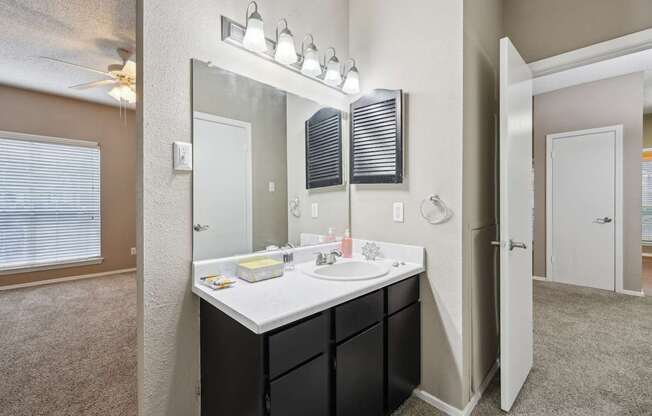 A bathroom with a sink, mirror, and lighting fixture.