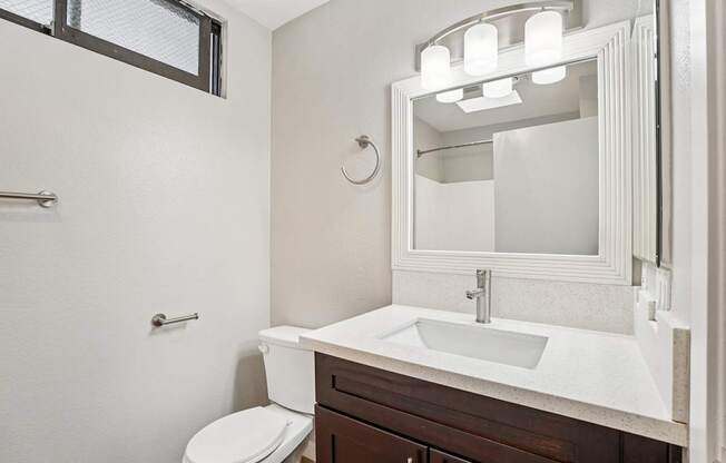 A white sink is in a bathroom with a toilet and a mirror.