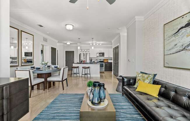 A modern living room with a black leather couch and a dining table set up.