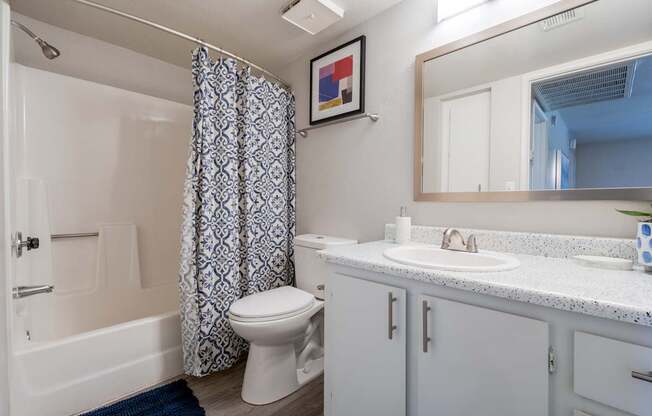 A white bathroom with a blue rug and a white toilet.