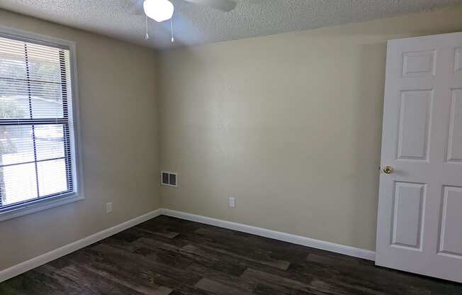 an empty living room with a ceiling fan and a window