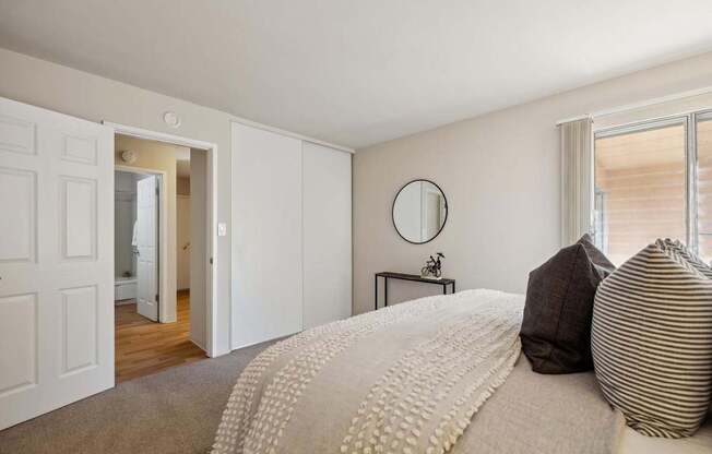 A bedroom with a large bed and a round mirror on the wall.