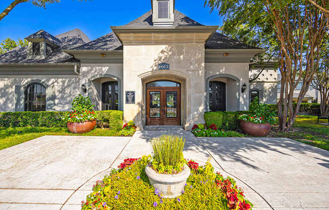 the front of a house with a driveway and potted plants