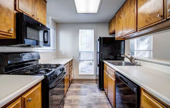 A kitchen with black appliances and wooden cabinets.