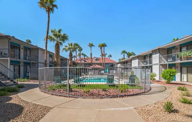 a round pool is in the middle of two apartment buildings with palm trees