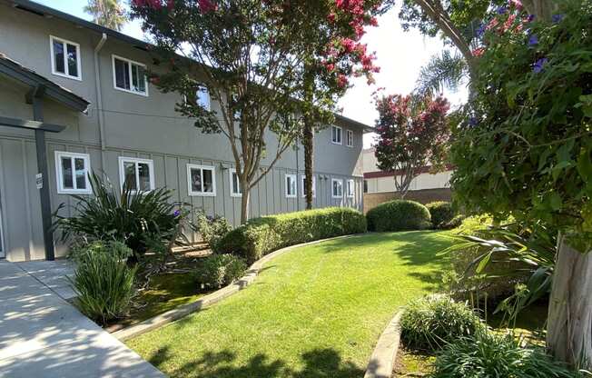 a yard with grass and trees in front of a building