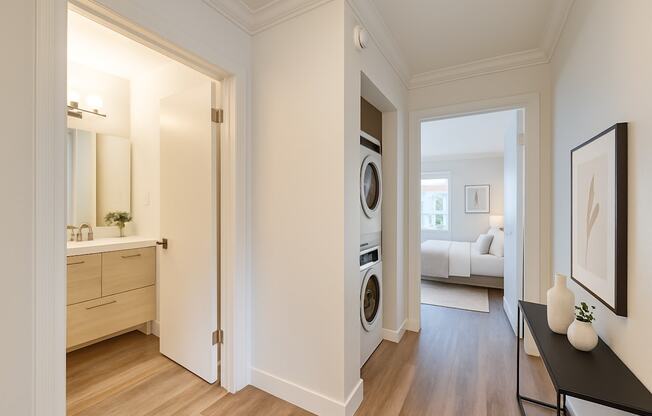 A hallway with a washing machine in the doorway.