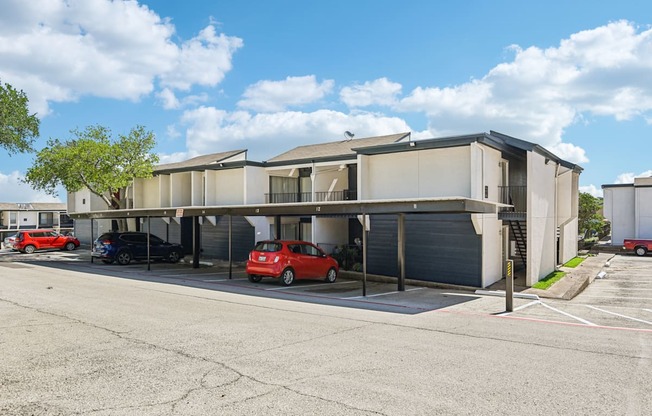 A parking lot with a building and cars parked in front.